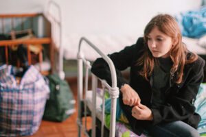 Girl sitting on bed in refugee camp